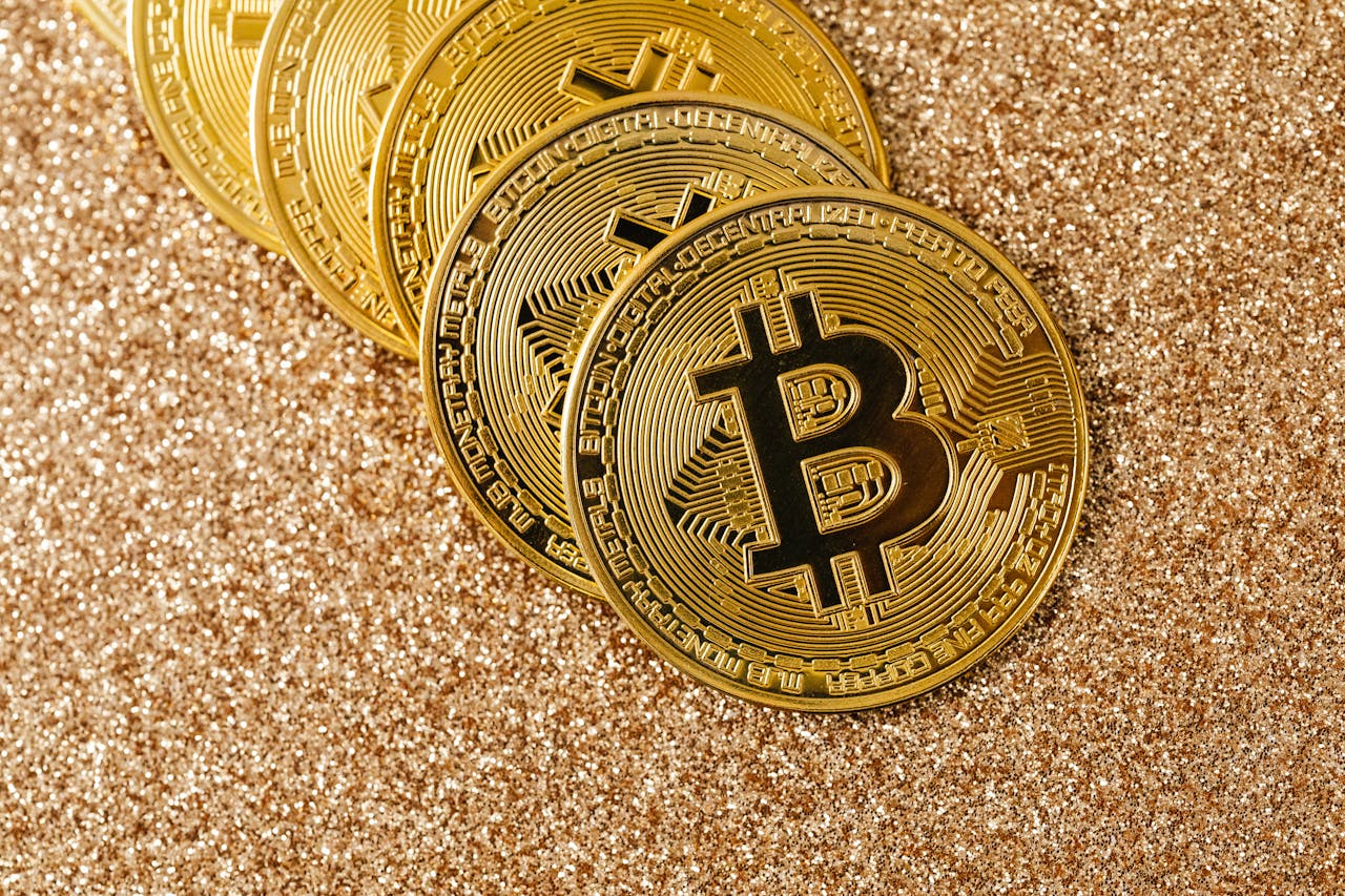 Golden Bitcoin coins arranged on a sparkling glitter surface, symbolizing cryptocurrency and wealth.